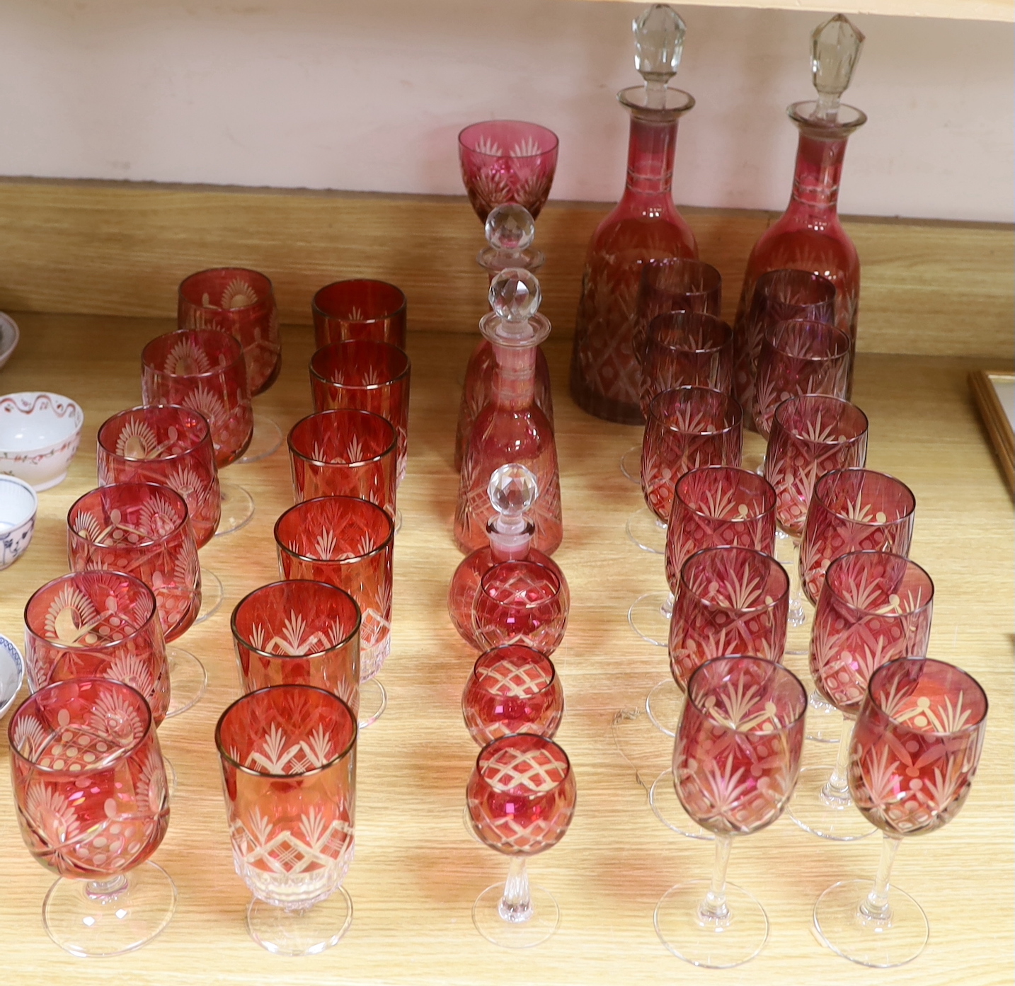 Cranberry glassware including a pair of cut glass decanters, together with a smaller pair and various suites of similar wine glasses, the largest 33cm high